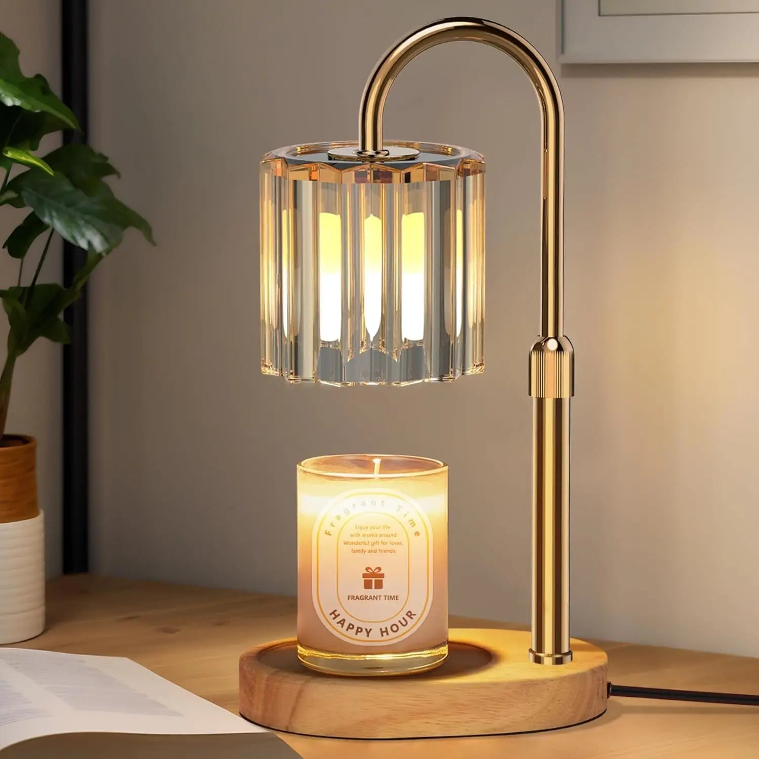 Modern gold candle warmer lamp with glass shade and lit candle on wooden desk