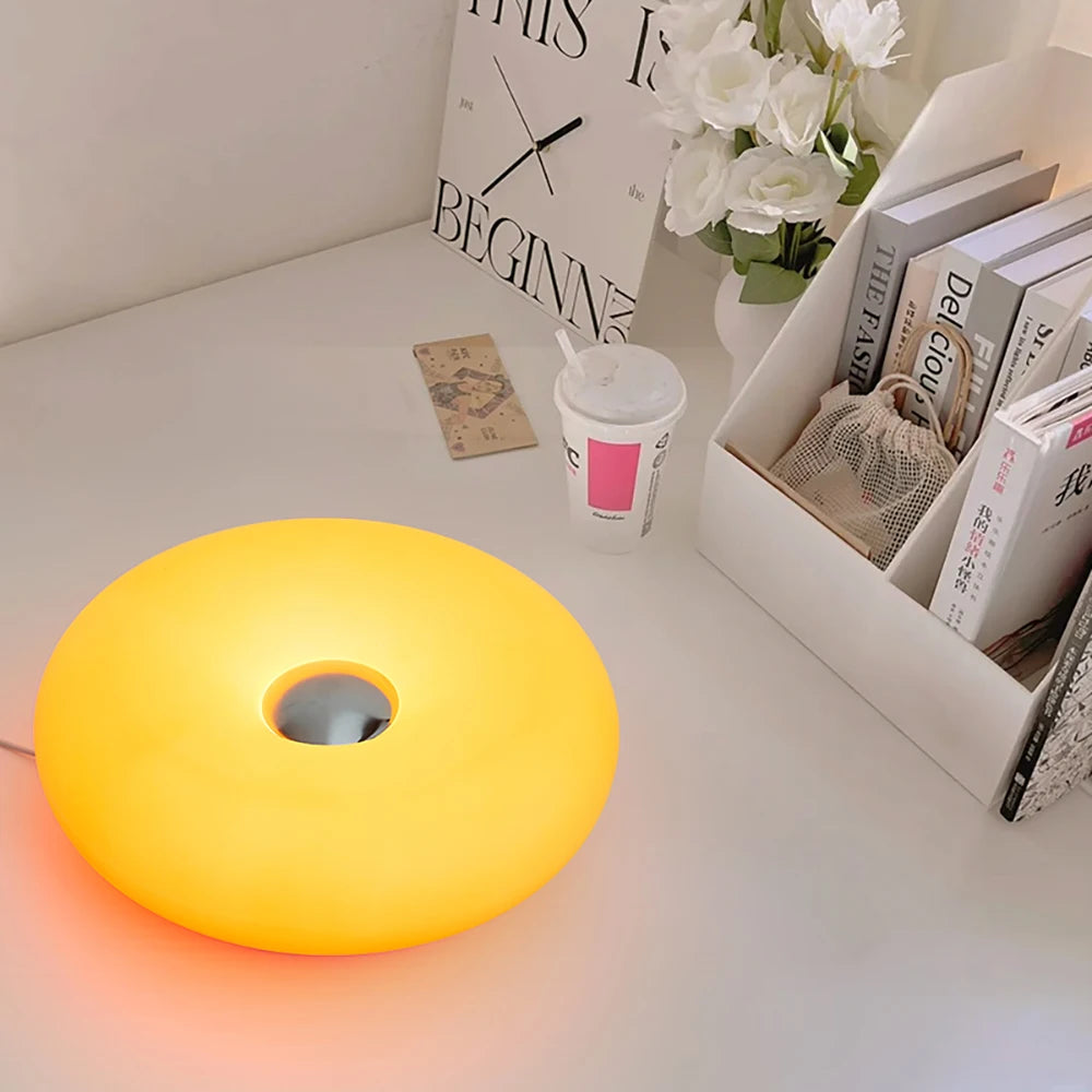 Modern orange round night light on minimalist desk with flowers and books